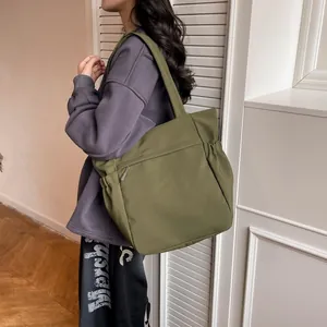Grande borsa tote verde oliva con tasche multiple indossata da una modella