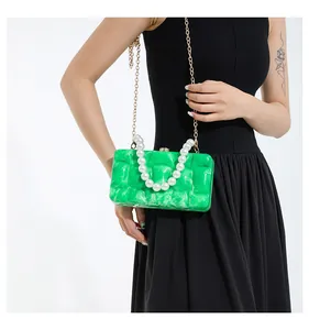 Detail of emerald green acrylic marble clutch with pearl handle and gold chain strap