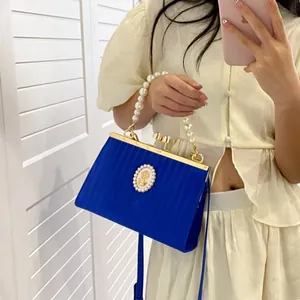 Sac à main bleu plissé avec poignée en perles et fermoir camée vintage porté par un mannequin