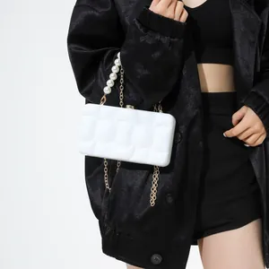 White acrylic evening bag with wave texture, pearl handle and gold chain strap