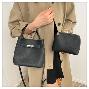 Detail of black lychee texture bucket bag and matching pouch held by model in trench coat