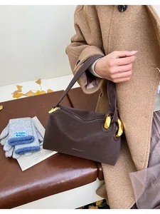 Dettaglio della borsa in pelle marrone retrò con anello dorato e accessori autunnali