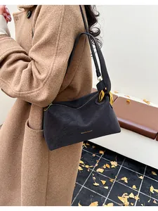 Dettaglio borsa a tracolla vintage nera con fibbie dorate su un cappotto cammello