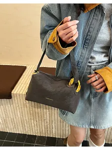Dettaglio della borsa grigio scuro con texture pietra, dettagli dorati e scritte