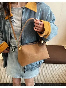 Dettaglio della borsa in pelle marrone testurizzata con finiture dorate e logo