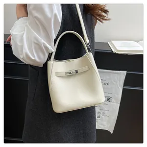 Detailed macro view of the cream lychee grain leather bucket bag with metallic twist lock