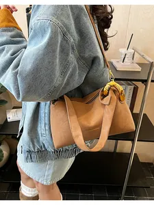 Dettaglio borsa in pelle marrone con fibbie in metallo dorato e stampa logo nero