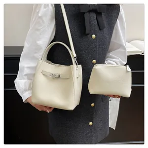 Detail of off-white lychee texture bucket bag with silver buckle on a female model