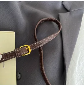 Detail of dark brown lychee pattern leather strap with white stitching and gold buckle