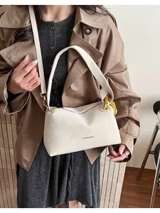 Dettaglio borsa a tracolla crema con catena d'oro e scritte su un cappotto marrone