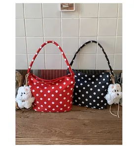 Close-up of red and black polka dot canvas underarm bags with cute plush dog charms