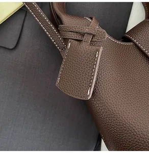 Detail of dark brown lychee leather handbag featuring white contrast stitching texture
