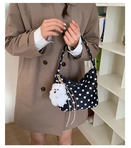 Polka dot hobo bag with plush dog charm worn over a classic khaki trench coat