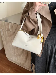 Dettaglio borsa hobo in pelle bianco crema con fibbia dorata e scritta su cappotto