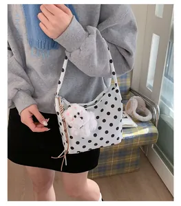 Close-up of polka dot shoulder bag with white puppy plush charm and brown tassel