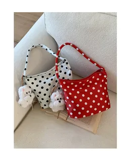 Detailed view of polka dot canvas underarm bags with cute plush dog charms on a sofa