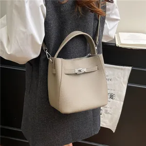 Taupe lychee-patterned bucket bag with metal turn-lock clasp and crossbody strap