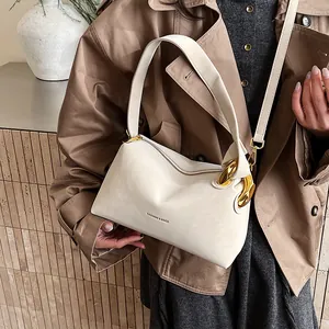 Borsa a mano vintage crema con dettagli dorati su un trench color kaki alla moda
