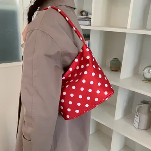 Chic red hobo bag with white polka dots on model in minimalist interior setting