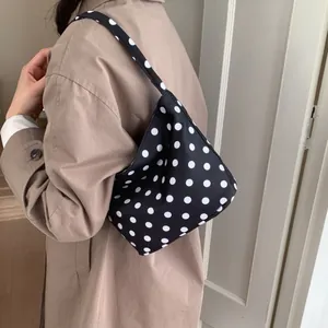 Chic black polka dot canvas underarm shoulder bag for women worn with khaki coat
