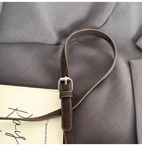 Macro detail of dark brown litchi leather strap with red stitching and silver buckle