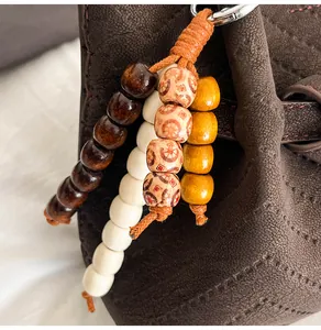 Detailed view of handmade ethnic wooden bead pendant on brown leather tote bag handle