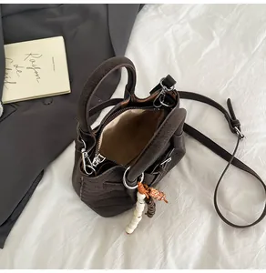 Detail view of coffee brown tote with V-quilt stitching and bead bag charm