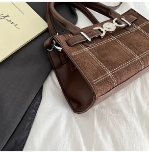 Dettaglio della borsa vintage marrone con cuciture a quadri e chiusura a cuore in metallo