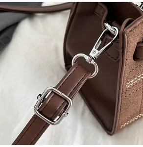 Dettaglio della tracolla regolabile con ganci in metallo argentato su borsa in pelle marrone