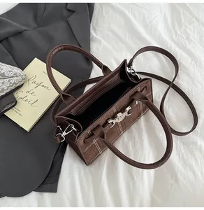 Dettaglio della borsa tote marrone scuro opaco con cuciture bianche e fibbia d'argento