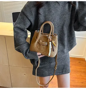 Detailed shot of brown suede tote with V-quilted stitching and beaded charm accessory