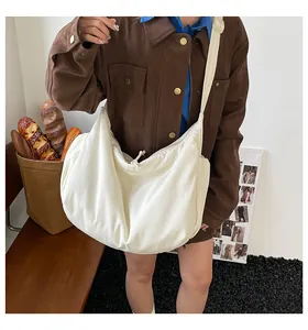 Photo lifestyle d'un sac besace blanc en toile avec cordon de serrage et large bandoulière
