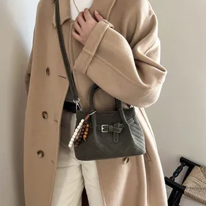 Olive suede bucket handbag with wooden bead charm and long shoulder strap for women