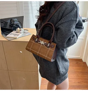 Dettaglio della borsa tote marrone a quadri con ricami raffinati e chiusure metalliche
