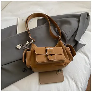 Detailansicht der braunen Wildledertasche mit silbernem Schloss-Anhänger und Taschen