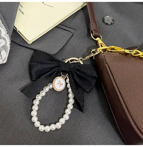 Dettaglio charm per borsa con fiocco di velluto nero e perle su borsa marrone