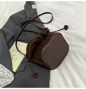Detail of suede bucket bag featuring drawstring closure and heart-shaped pendant