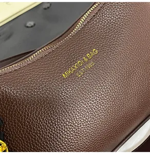 Dettaglio della pelle marrone martellata con logo dorato e cerniera in metallo pregiato