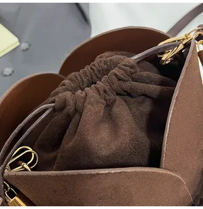 Detail view of dark brown suede bucket bag featuring premium gold hardware and drawstring