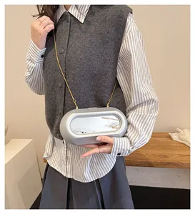 Sac capsule argenté à effet miroir avec bandoulière chaîne dorée porté sur modèle