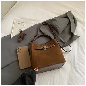Vue détaillée d'un sac seau en daim marron avec détails en cuir et fermoir rotatif en métal