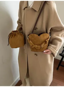 Close-up of suede bucket bag with decorative floral handle and removable drawstring pouch