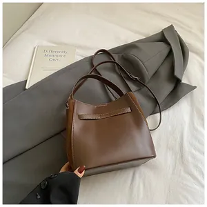 Détail du sac seau marron foncé avec contraste de cuir lisse et texture suédée