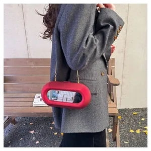 Sac capsule rouge mat avec miroir intégré et chaîne dorée porté par un mannequin