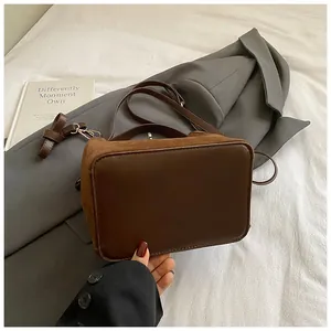 Détail d'un sac seau marron vintage montrant des textures daim et cuir lisse
