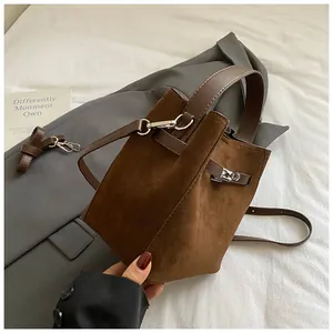 Gros plan détaillé du sac seau en daim marron foncé avec bandoulière en cuir et métal