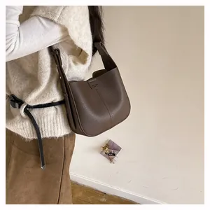 Détail d'un sac seau en cuir marron foncé avec texture grainée et coutures minimalistes