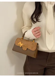 Detail of retro suede handbag with gold M-letter charm and G-shaped metal buckle