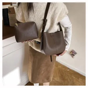 Vue détaillée du sac seau en cuir litchi marron foncé avec petite pochette zippée assortie