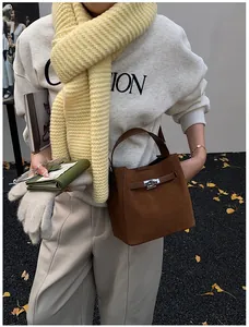 Détail d'un sac seau en daim marron avec sangle en cuir et fermoir en métal en décor d'automne